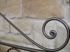 wrought iron bed against stone wall